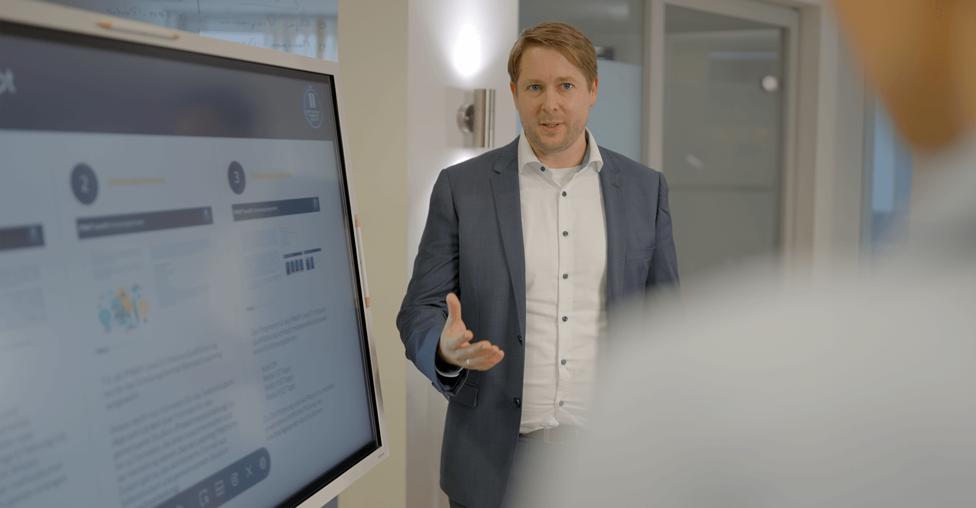 Markus Hegeler stellt einem Mitarbeiter die Vorteile des Prozessmanagements durch die PEC anhand einer Präsentation vor.